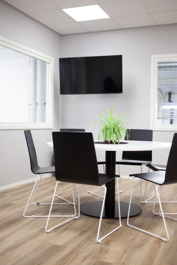 Yrityksen taukotila, jossa pyöreän pöydän takana on infonäyttö seinällä