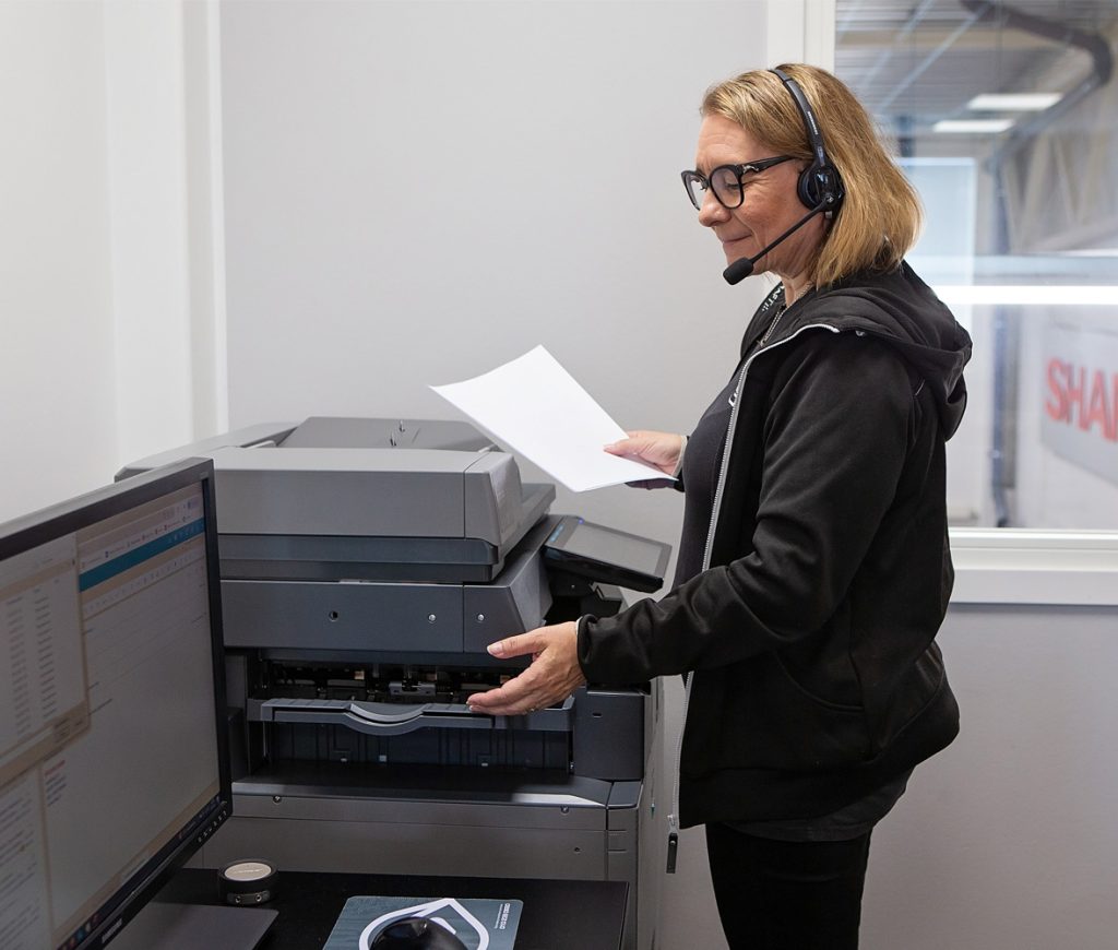 Nainen monitoimilaitteen ääressä ottamassa tulosteita laitteen sisältä